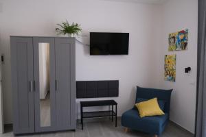 a living room with a tv and a blue chair at Nel Corso del Sogni Sicily Center Rooms in Campofelice di Roccella