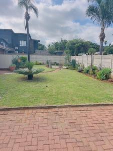 a lawn with palm trees in a yard at Mangena Legacy Guesthouse in Polokwane