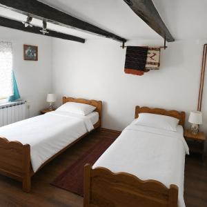 two beds in a bedroom with white walls and wooden floors at Country house in nature -10 min from Nikola Tesla Memorial Center-peace and privacy in Klanac +11 photos