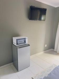 a microwave sitting on top of a refrigerator in a room at Mangena Legacy Guesthouse in Polokwane