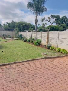 a backyard with a brick driveway and a white fence at Mangena Legacy Guesthouse in Polokwane +10 photos