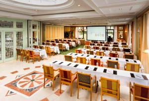 a large room with tables and chairs and a screen at Hotel Parc Belair in Luxembourg