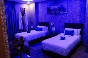 two beds in a room with purple walls at Hotel Cafe Sahariano in Smara +15 photos