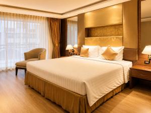 ein Hotelzimmer mit einem großen Bett und einem Stuhl in der Unterkunft Nova Gold Hotel Pattaya in Pattaya