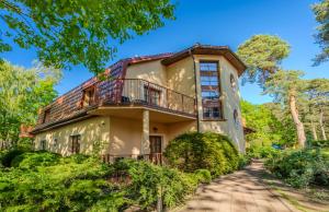 a large house with a balcony and trees at Wy & Spa in Pobierowo