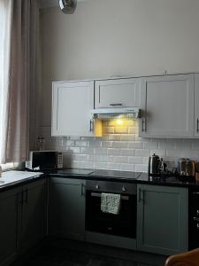 a kitchen with white cabinets and a stove top oven at Carnegie Library: Bronte Apartment 1 Bedroom in Swinton +7 photos