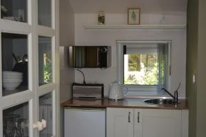 a kitchen with a counter with a microwave and a sink at Cozy Cottage in Schoorl +48 photos