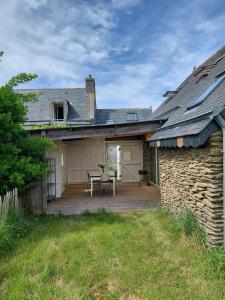 a house with a wooden deck with a table at Penty vue sur mer in Tréguennec