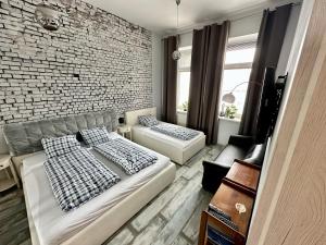 a room with two beds and a brick wall at Royal City Centre Apartment - 2 Bedrooms 72 m2 - AC - Balcony - Coffee Machine - Washer - Dryer -Parking available Free public or Paid Private for 20 euro per stay Please read our emails in Poprad
