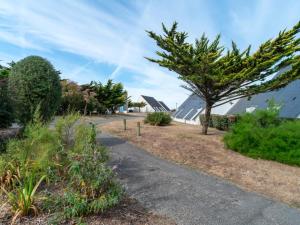 a path in a garden with a tree and buildings at Sud Ocean J N74 2P4 in Guidel