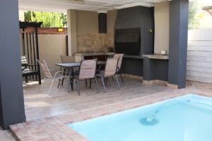 a patio with a table and chairs next to a swimming pool at Gemutlich Guesthouse in Upington