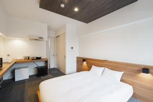 a bedroom with a white bed and a desk at HIT Tenjin in Fukuoka