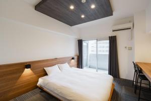 a bedroom with a bed and a desk and a window at HIT Tenjin in Fukuoka