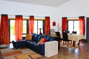 a living room with a leather couch and a table at Villa Penim - Countryside Villa with Jacuzzi, Garden with BBQ & Stunning Views in Sesimbra