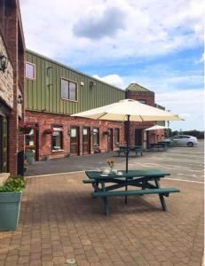 a picnic table with an umbrella in front of a building at Tara View Apartments in Garristown