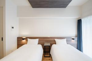 two beds in a room with a window at HIT Tenjin in Fukuoka +28 photos