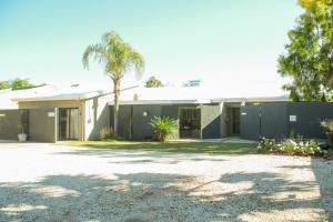 a house with a palm tree and a driveway at Gemutlich Guesthouse in Upington