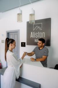 a woman shaking hands with a man at a counter at Aliston Hotel Thassos in Skala Potamias