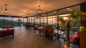 ein Restaurant mit Tischen, Stühlen und Fenstern in der Unterkunft Bungaport Luxury Bungalows&Suits in Rize