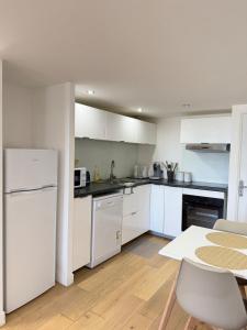a white kitchen with white appliances and a table at Douceur Suite - 2 bedrooms in Mâcon