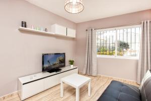 a white living room with a tv and a table at Doña Elena in Fuengirola