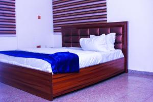 a bed with a wooden frame with a blue blanket on it at G Point Hotel Ikeja in Mama