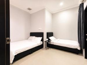 two beds in a room with white walls at UMii Homestay in Tawau