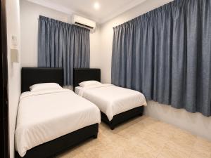 two beds in a room with blue curtains at UMii Homestay in Tawau