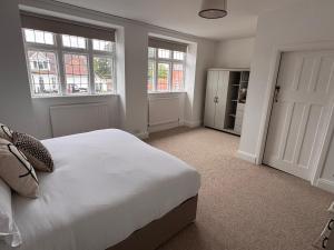 a bedroom with a white bed and two windows at The Wrey Arms in Barnstaple
