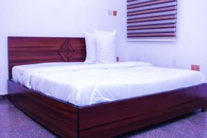 a bed with a wooden headboard in a bedroom at G Point Hotel Ikeja in Mama