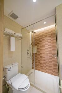 a bathroom with a toilet and a glass shower at Kotta Kyu Hotel Semarang in Semarang