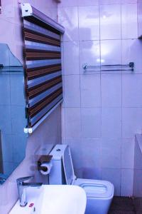 a bathroom with a white toilet and a sink at G Point Hotel Ikeja in Mama +13 photos