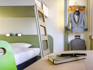 a bedroom with a bunk bed and a desk with a book at ibis budget Berlin Ost in Berlin