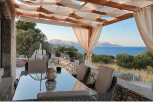 a dining table with chairs and a view of the ocean at Anemoessa Stone House in Kokkala