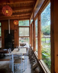 a dining room with a table and chairs and windows at Glamp Refugio Silvestre 7 Tazas in Molina