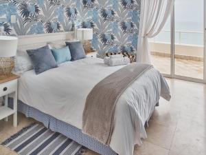 a bedroom with a bed with a blue and white wallpaper at Unit 1101 Oyster Rock in Durban +30 photos