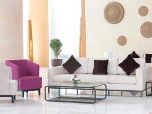 a living room with a white couch and two chairs at Novotel Jazan in Jazan