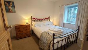 a bedroom with a bed with a dresser and a window at Mews Cottage in Middleton in Teesdale +28 photos