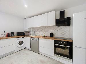 a kitchen with white cabinets and a washer and dryer at Appartement 4 personnes in Cholet