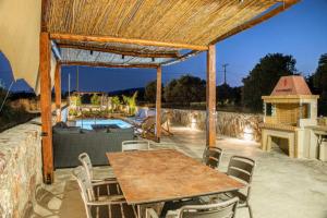 a patio with a table and chairs and a fireplace at Dreamy Charaki 2 Bd Villa with Private Pool in Haraki