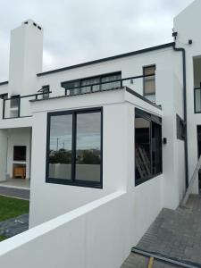 a white house with black windows at Kwagga Inn in Stompneusbaai