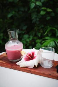 a drink in a glass vase and a flower on a wooden tray at Bungalow l'escapade in Entre-Deux
