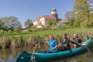 three women are in a canoe on the water at ahead burghotel in Lenzen