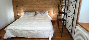 ein Schlafzimmer mit einem weißen Bett und einer Holzwand in der Unterkunft Lu Biulè Ca' d'Aldo in Groscavallo