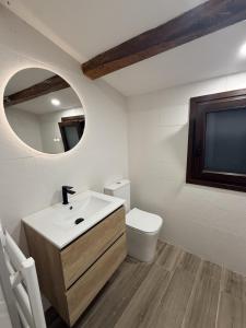 a bathroom with a sink and a toilet and a mirror at Jaca Stone in Banaguás +8 photos