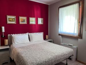 a bedroom with a white bed and a red wall at Agriturismo Papaveri & Papere in Caltana