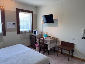 a hotel room with a bed and a table and a television at Agriturismo Papaveri & Papere in Caltana