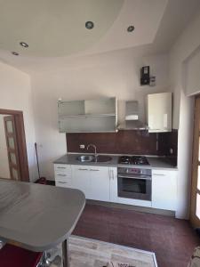 a kitchen with white cabinets and a sink and a table at Brane Apartmani in Zadar