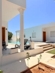 a villa with a swimming pool and a house at Résidence Azur Djerba in Taguermess