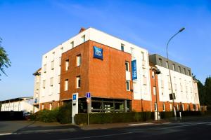 a large red brick building with a blue sign on it at ibis budget Saint-Omer Centre in Saint-Omer